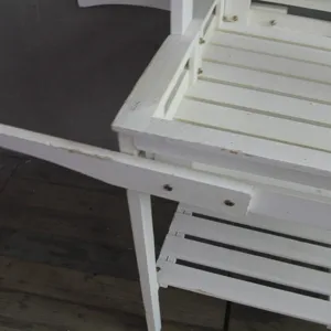 Gros plan sur la finition blanche vieillie d'un chariot à fleurs en bois de style champêtre.