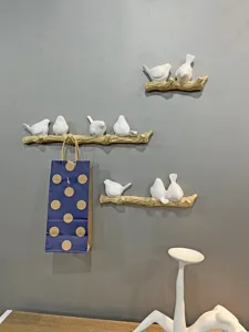 Creative bird on branch wall hooks shown holding a blue paper bag for storage.