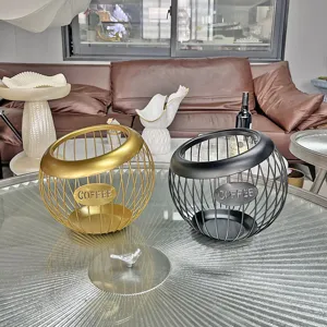 Detailed view of gold and black wire iron coffee capsule organizers on glass table