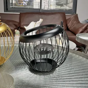 Close-up of a black metal wire coffee capsule holder on a glass table