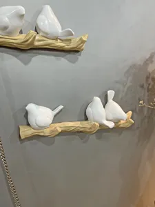 Detail view of decorative wall hooks featuring white birds on a light brown branch