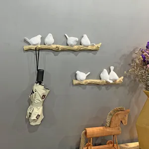 Creative white bird on branch wall hooks displayed in a stylish home entryway setting