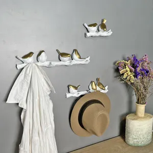 Detail view of creative bird-on-branch wall hooks holding a white shirt and a hat