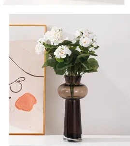 Vue détaillée de fleurs de géranium artificielles blanches dans un vase en verre brun