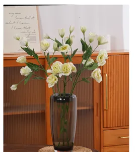 Detailed shot of artificial white Lisianthus flowers in a smoky grey glass vase