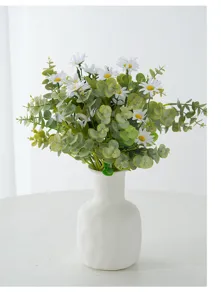 Elegant artificial white daisy bouquet with green eucalyptus leaves in a white ceramic vase