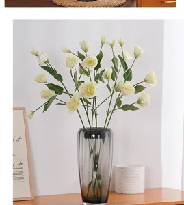 Detailed view of cream-colored artificial Eustoma flowers in a stylish grey glass vase