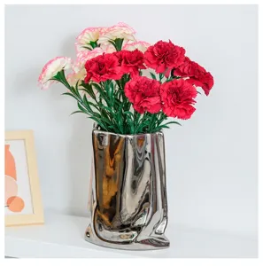 Detailed view of red and pink artificial carnations in a stylish silver metallic vase