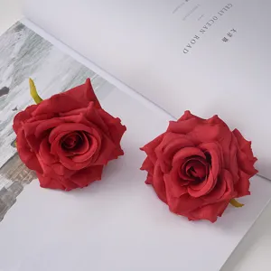 Detailed macro view of two red silk artificial rose flower heads on an open white book.