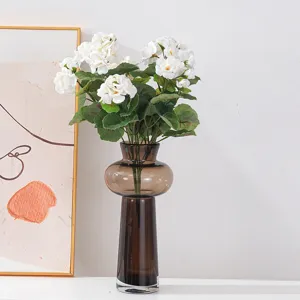 Arrangement d'hortensias blancs artificiels dans un vase en verre brun pour la déco.