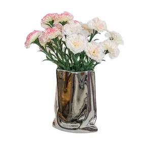 Elegant artificial carnation flower arrangement in a silver metallic paper bag vase