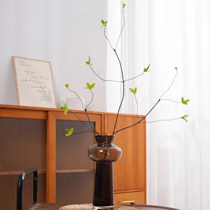 Realistic artificial green leaf branches in a stylish brown glass vase for home decor