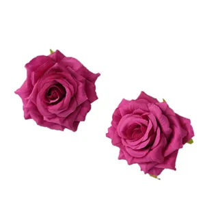 Two magenta artificial silk rose heads with curled petals on a white background.