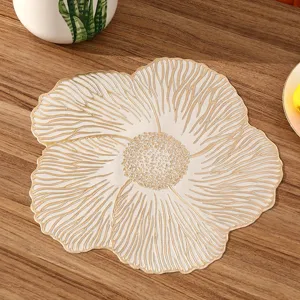 Close-up of a flower-shaped PVC placemat with gold textures on a wooden table