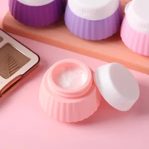 Detail macro shot of an open pink cupcake-shaped silicone travel jar with white lid