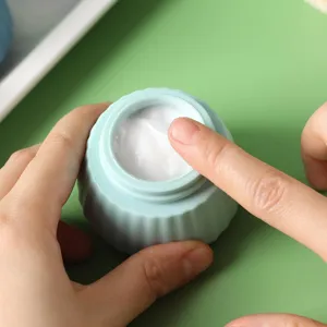 Close-up detail of white face cream inside a light blue soft silicone travel jar.