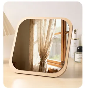 Detalle de un espejo de mesa cuadrado de madera que refleja una acogedora ventana de cuarto