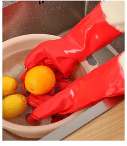 Vista detallada de guantes rojos impermeables forrados de felpa lavando fruta en el fregadero