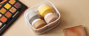 Cupcake-shaped silicone travel bottles in a transparent pouch with makeup props