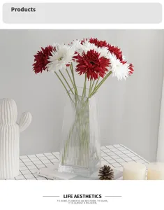 Detailed view of red and white artificial African daisies in a glass vase