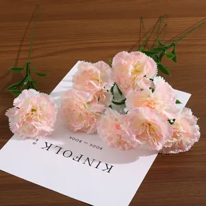 Vue détaillée de fleurs d'œillets artificiels roses sur un fond blanc minimaliste
