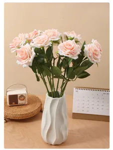 Detailed view of elegant artificial pink roses in a stylish wavy white ceramic vase for home decor