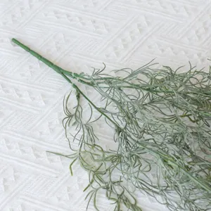 Detailed view of artificial green air vine plant on white textured fabric surface