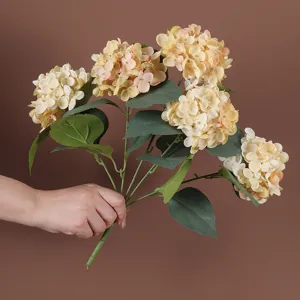 Detailweergave van hand die een boeket van vijf kunstmatige hortensia's vasthoudt