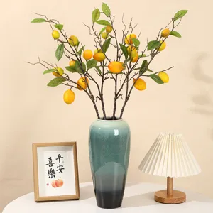 Artificial lemon branches with yellow fruits in a blue ceramic vase for home decor