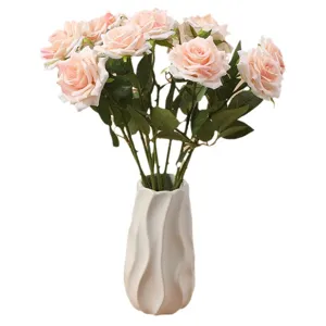 Elegant artificial champagne roses with realistic curled edges in a white vase.