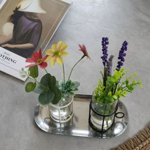 Elegant glass vase ornaments with metal frames displayed on a stainless steel tray