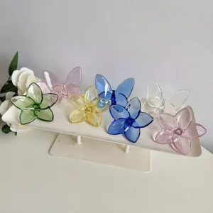 Assorted colorful crystal glass flower and butterfly ornaments on a white display stand