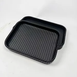 Detailed macro view of two rectangular black trays with elegant woven leather texture