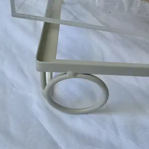 Detalle del marco de hierro crema y el pie circular del soporte para postres acrílico.