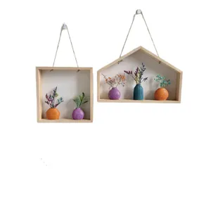 Moderne houten wandplanken voor schaduwboxen met kleurrijke vazen en gedroogde bloemstukken