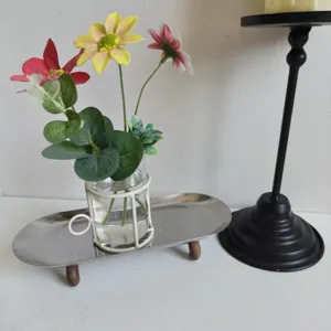 Detail view of a creative glass vase in white iron wire frame on a silver metal tray.