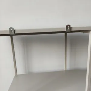 Détail des supports de montage métalliques sur le bord supérieur d'une étagère en fer gris.