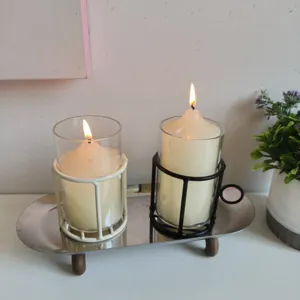 Elegant metal wire candle holders with glass inserts on a minimalist silver tray