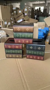Détail de trois boîtes à mouchoirs vintage en bois en forme de livres posées sur carton.