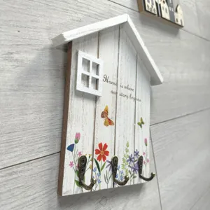 Detailed view of Nordic wooden house hook with floral print and Home quote.