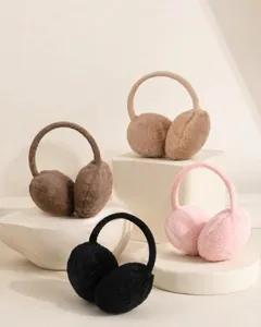 Plush winter earmuffs in four colors displayed on minimalist cream stone pedestals