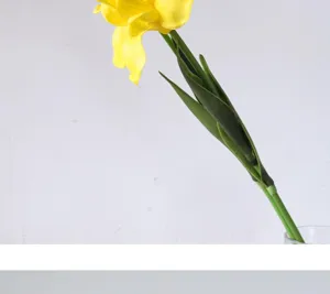 Artificial PU iris flower stem detail, yellow bloom and green leaves closeup view.