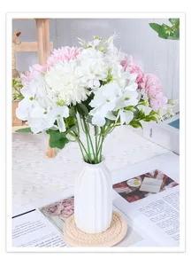 Detailed view of artificial white and pink flower bouquet in a modern white ribbed vase