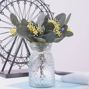 Close-up of artificial eucalyptus branch with yellow berries in a glass vase