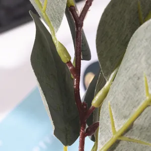 Close-up detail of artificial eucalyptus stem with green leaves and small fruits.