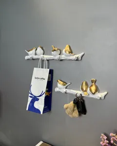 Detail view of decorative white and gold bird on branch wall hooks for bags and keys