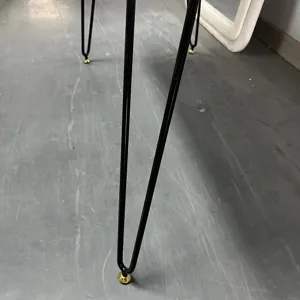 Detail of modern black hairpin legs with gold adjustable feet on a vanity desk