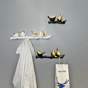 Detail view of creative bird branch wall hooks holding a white shirt and a gift bag