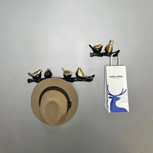 Decorative bird on branch wall hook showing hat and bag hanging
