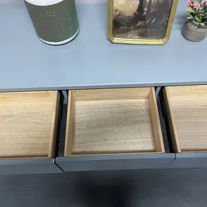 Detail of modern gray vanity cabinet showing three open wooden drawers with metal slides